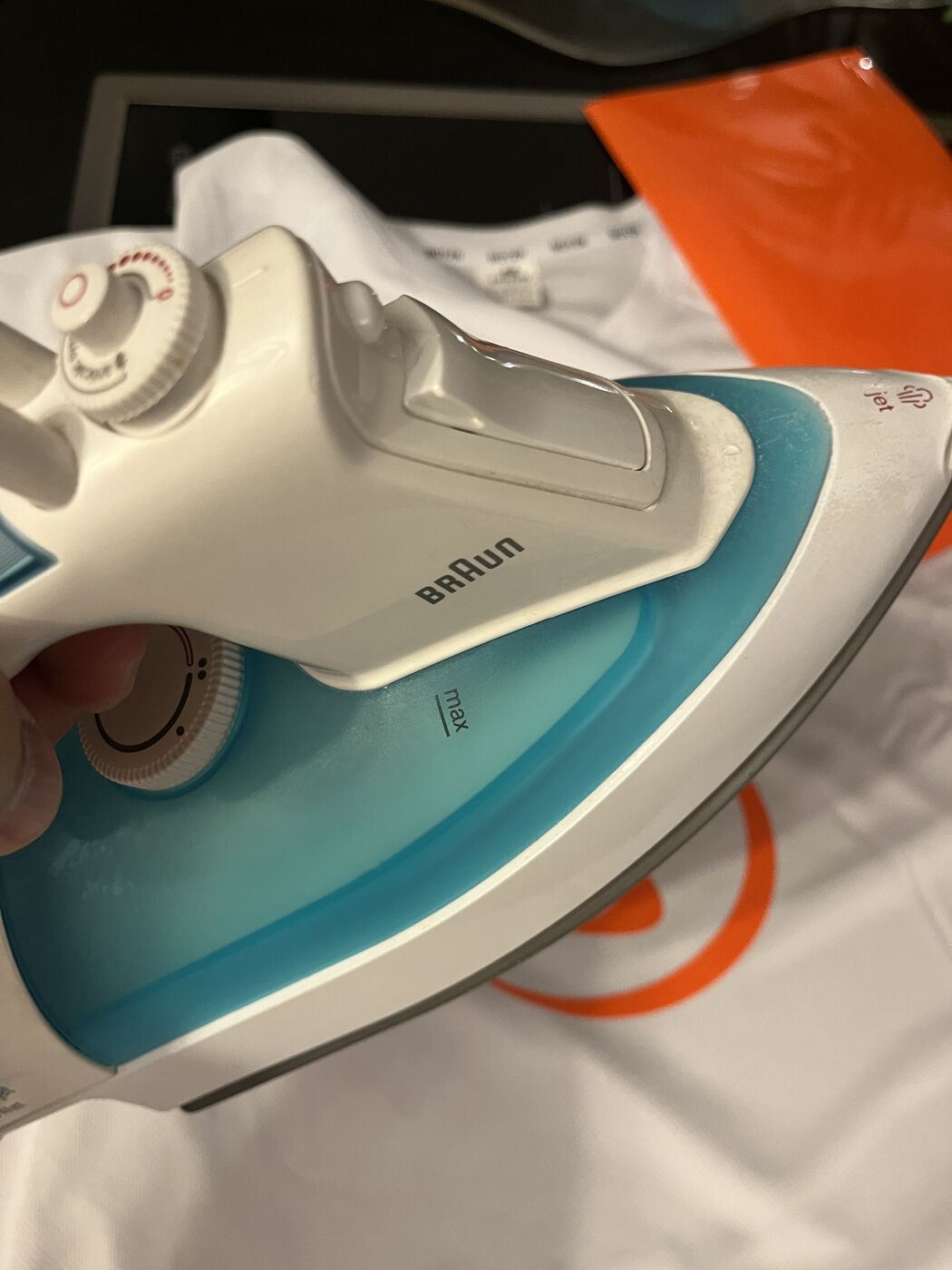Orange Flexfolie wird mit dem Bügeleisen auf ein weißes Laufshirt aufgebracht