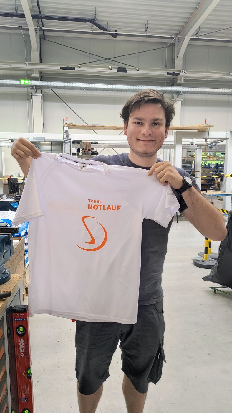 Stranger-Mitarbeiter in der Montagehalle mit dem Laufshirt von Team NOTLAUF
