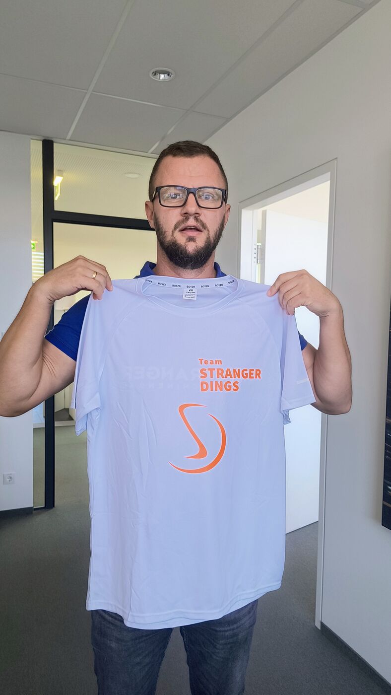 Stranger-Mitarbeiter präsentiert das Laufshirt von Team STRANGER DINGS