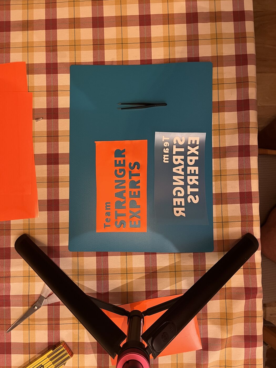Flexfolien-Schriftzug Team STRANGER EXPERTS wird mit der Pinzette entgittert