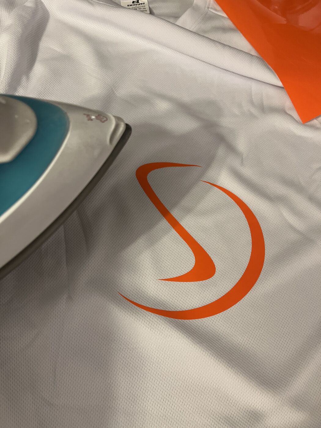 Fertig aufgebrachtes Stranger-Logo in Orange auf weißem Laufshirt