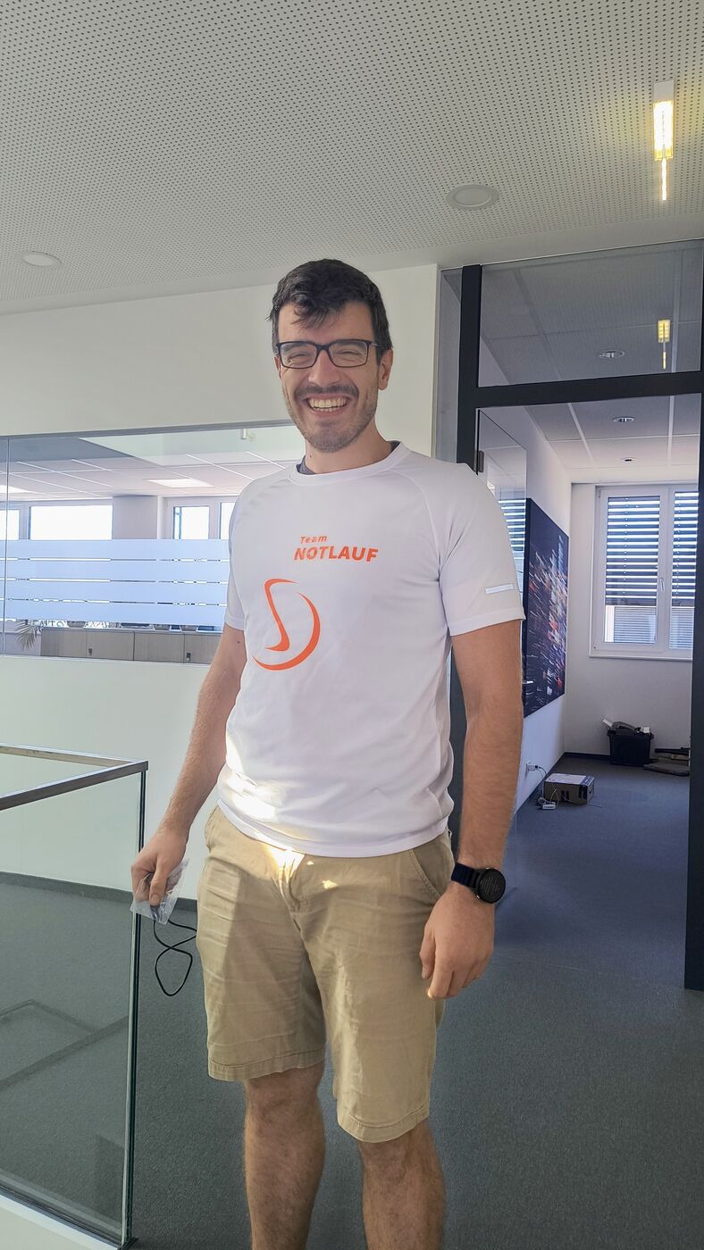 Stranger-Mitarbeiter im Büro mit dem Laufshirt von Team NOTLAUF für den Salzburger Businesslauf 2026