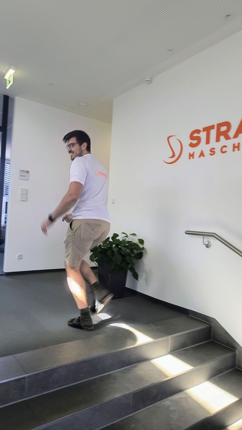 Läufer im Stranger-Laufshirt vor dem Firmenlogo im Stiegenhaus