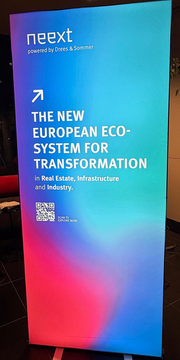 Beleuchteter Roll-up von neext, powered by Drees & Sommer, mit dem Text „The new European Eco-System for Transformation“