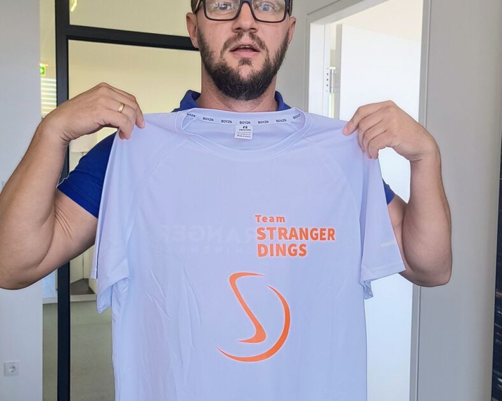 Stranger-Mitarbeiter präsentiert das Laufshirt von Team STRANGER DINGS